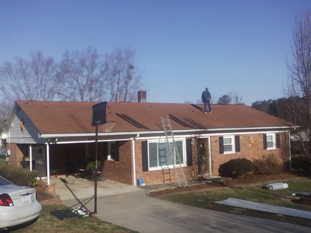 Roofer stripping a shingle roof on a brick ranch before metal panels in Dewey