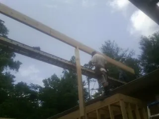 Carpenter setting a ridge beam over a new addition frame — Ice Dam Removal by Roofing Brothers in Dewey