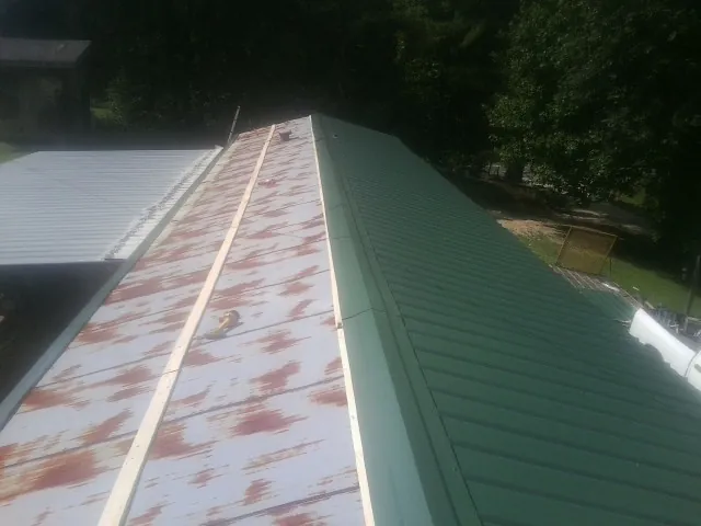 Old rusted panels beside newly installed green metal roofing — Wind Damage Roof Repair by Roofing Brothers in Dewey