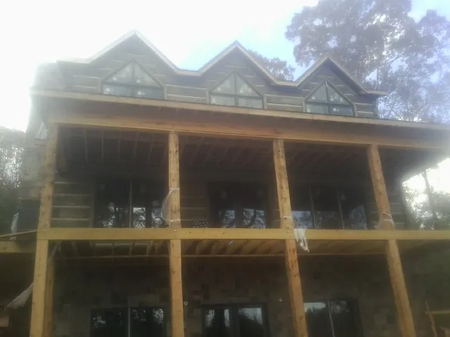 Dormers and porch framing on a large log home under construction — Roof Coating work by our crew in Dewey