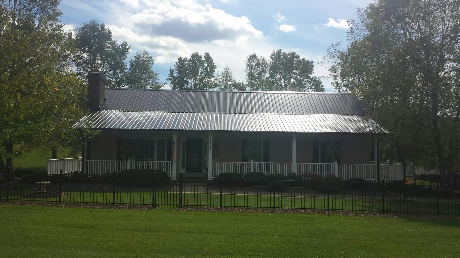 Gray metal roof on a brick ranch with a full width front porch — Gutter Guard Installation work by our crew in Dewey