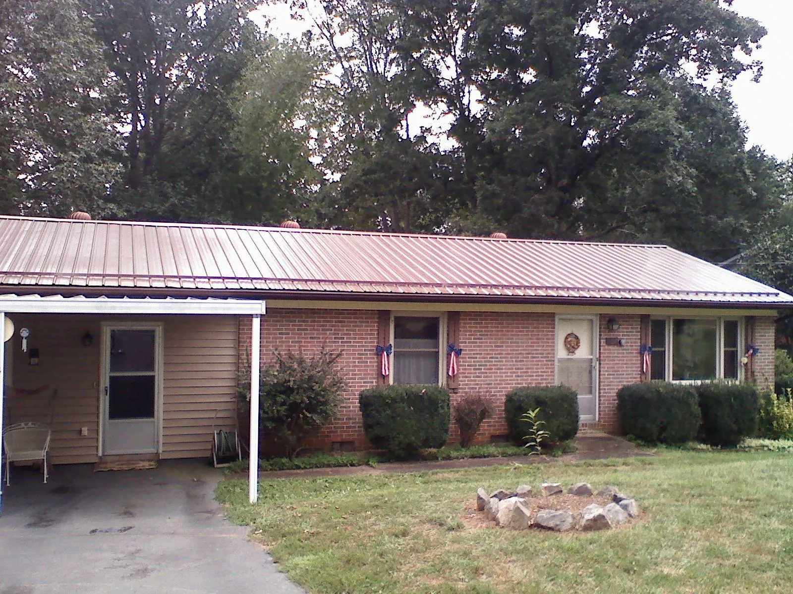 Bronze metal roof and carport on a brick ranch home — Roof Repair work by our crew in Dewey